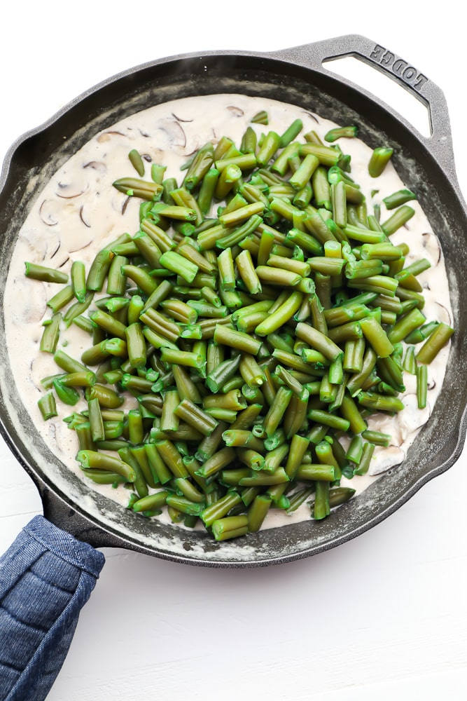 green beans going into pan with mushroom sauce