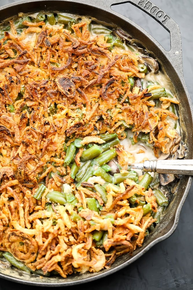 looking down on a cast iron pan filled with green beans in sauce and fried onions