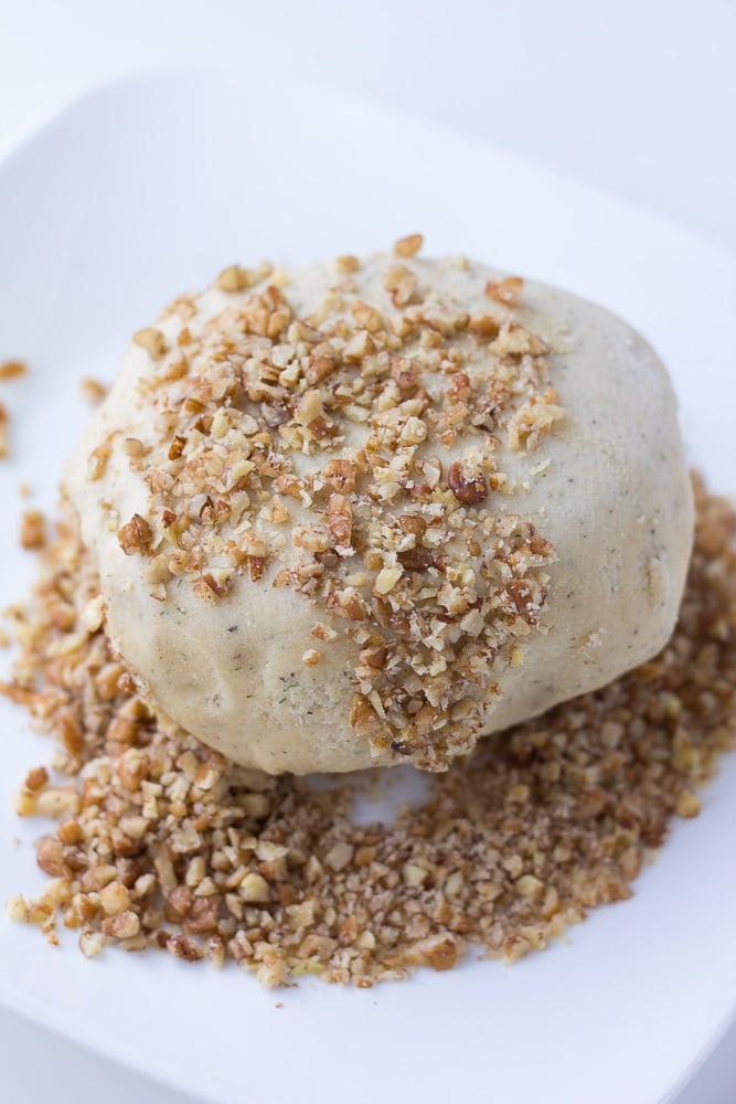 vegan cheese ball being rolled in nuts