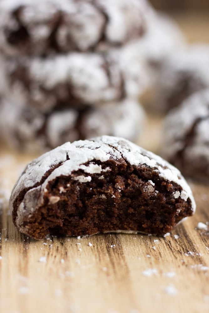 vegan chocolate crinkle cookies, 1 with a bite taken out up close shot.