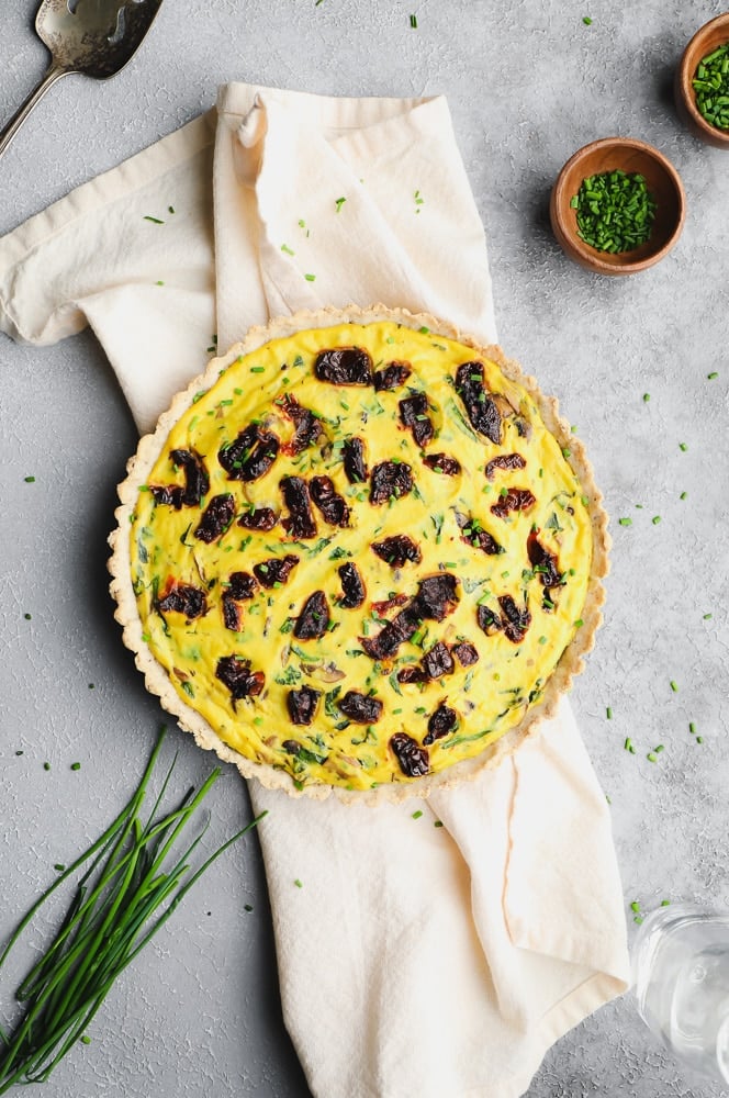 whole uncut quiche with sun dried tomatoes on top