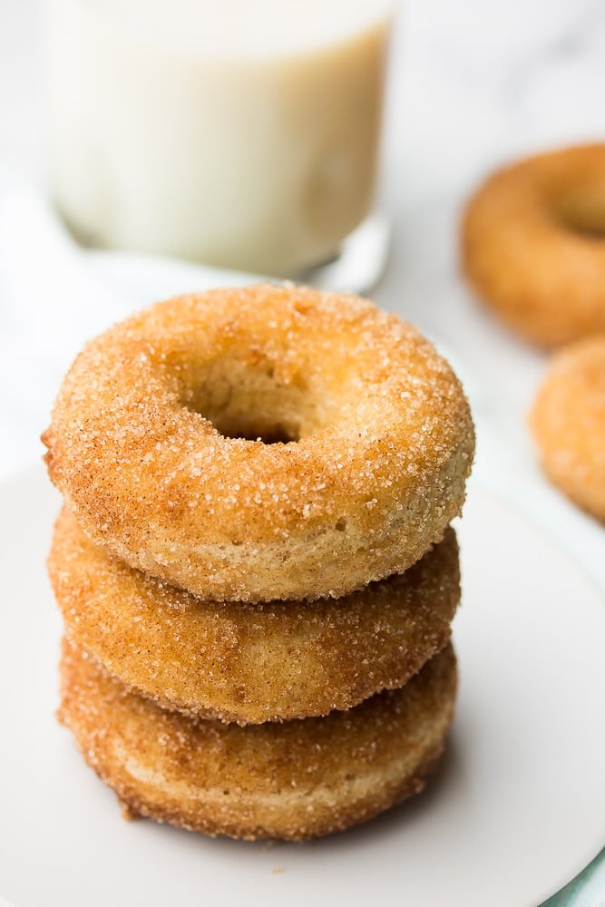 stack of vegan donuts, milk in a cup in background and more donuts