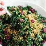 spoon scooping out some festive kale salad from bowl