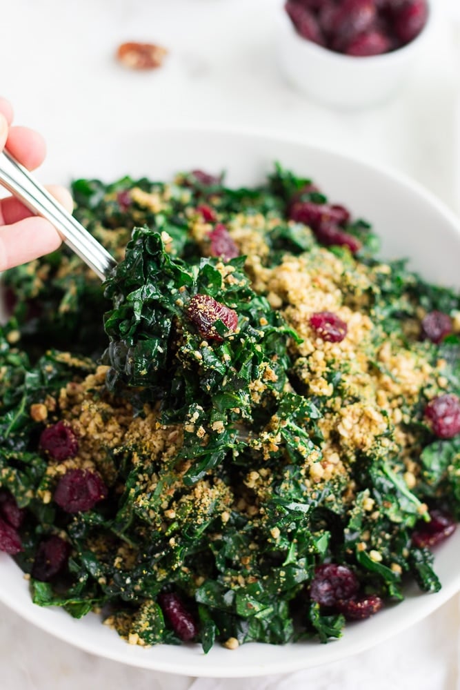 spoon scooping out some festive kale salad from bowl