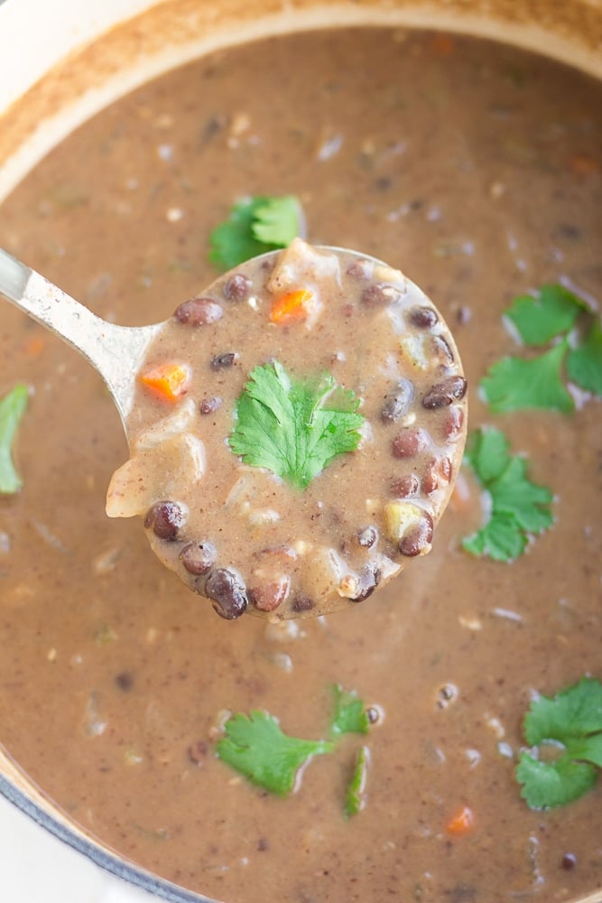 ladle with black bean soup taken from big pot