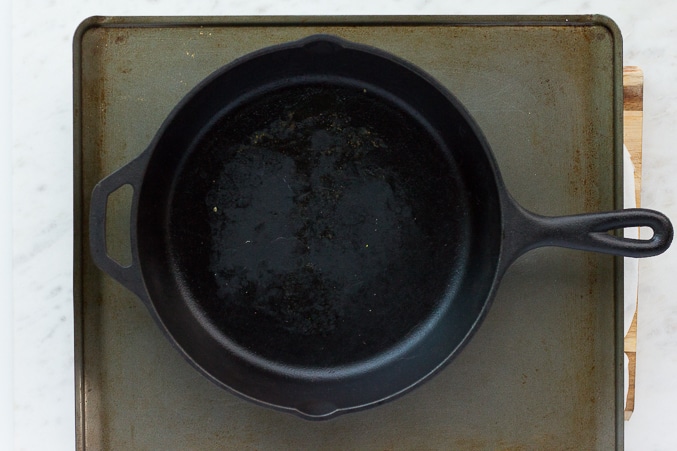 showing how to press tofu for marinated tofu, cast iron pan on sheet, tofu underneath