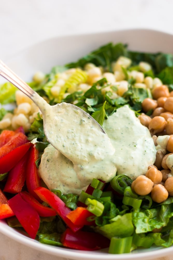 vegan green goddess dressing being spooned onto salad