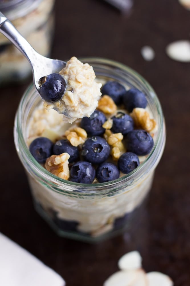 jar of vegan overnight oats with blueberries and walnuts with a spoonful
