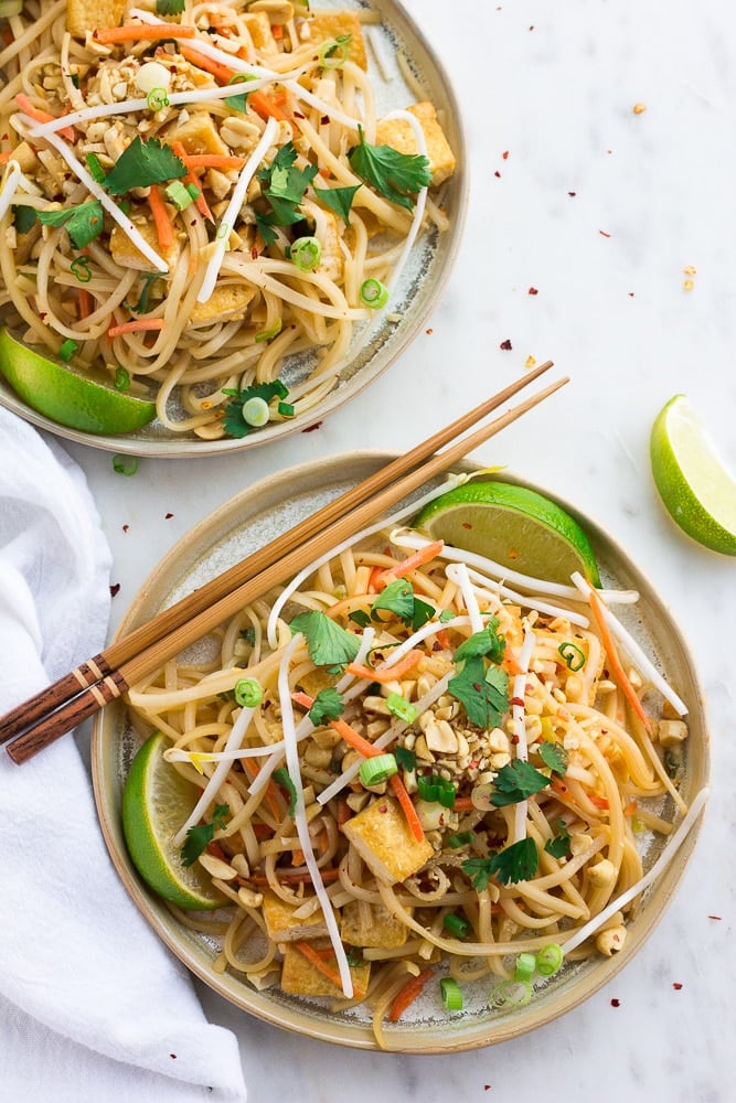 two plates with vegan pad thai from top with chopsticks