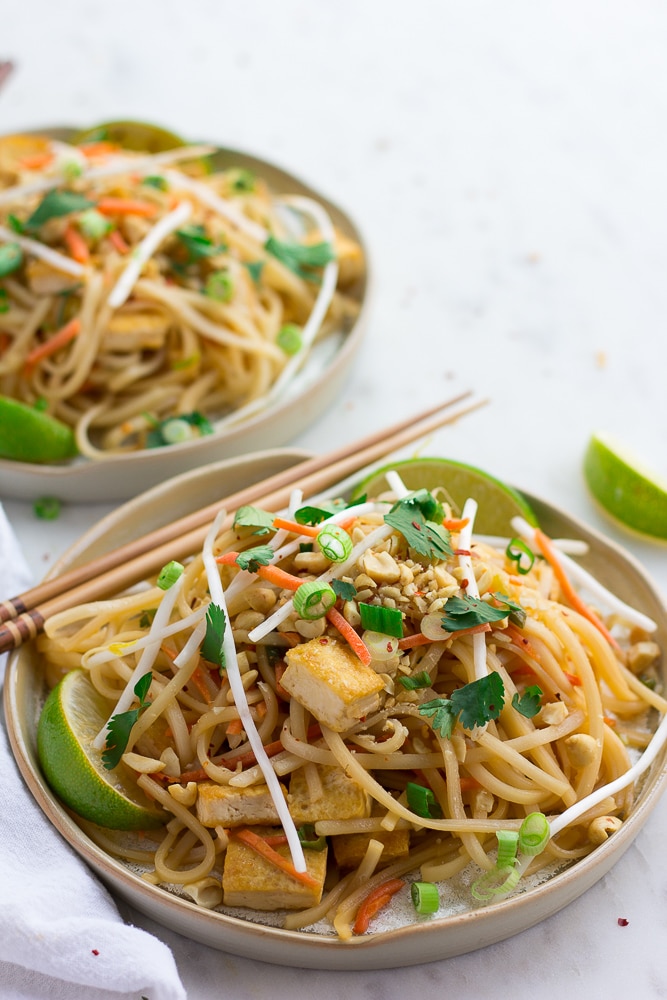 two plates with vegan pad thai on it with chopsticks