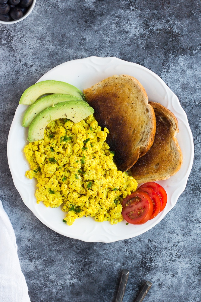 tofu scramble on a plate with avocado, tomato and toast