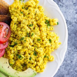 tofu scramble on a plate with avocado, tomato and toast