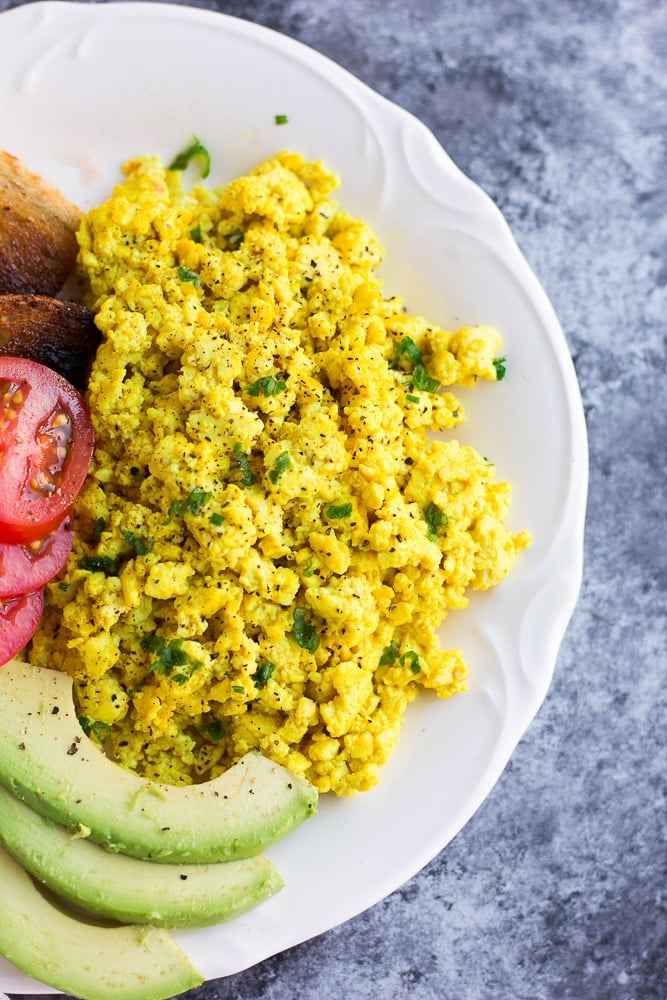 tofu scramble on a plate with avocado, tomato and toast