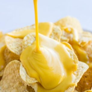 vegan cheese sauce being poured onto chips