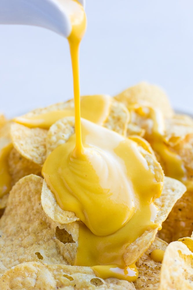 vegan cheese sauce being poured onto chips