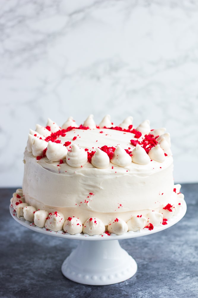 frosted vegan red velvet cake with white and gray background.