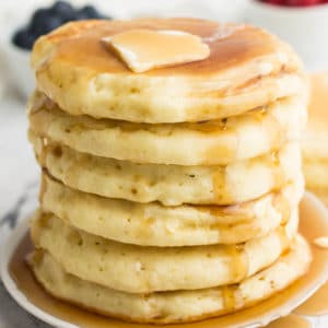 square image of stack of vegan pancakes with syrup and butter on top
