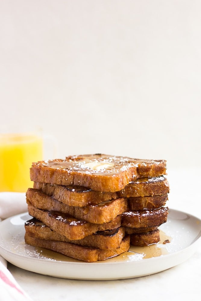 stack of vegan french toast with orange juice in background