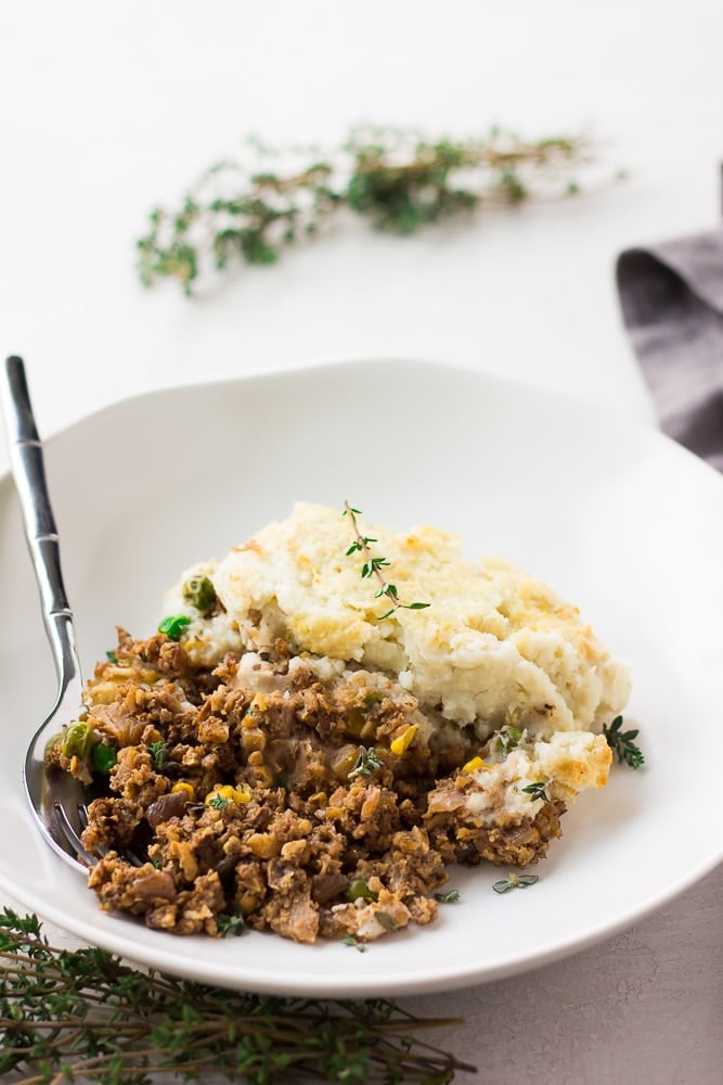 vegan shepherd's pie in a white bowl with a fork.
