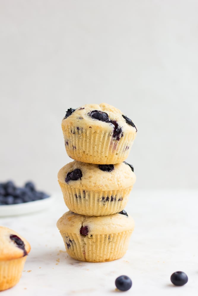 3 stacked vegan blueberry muffins white background.