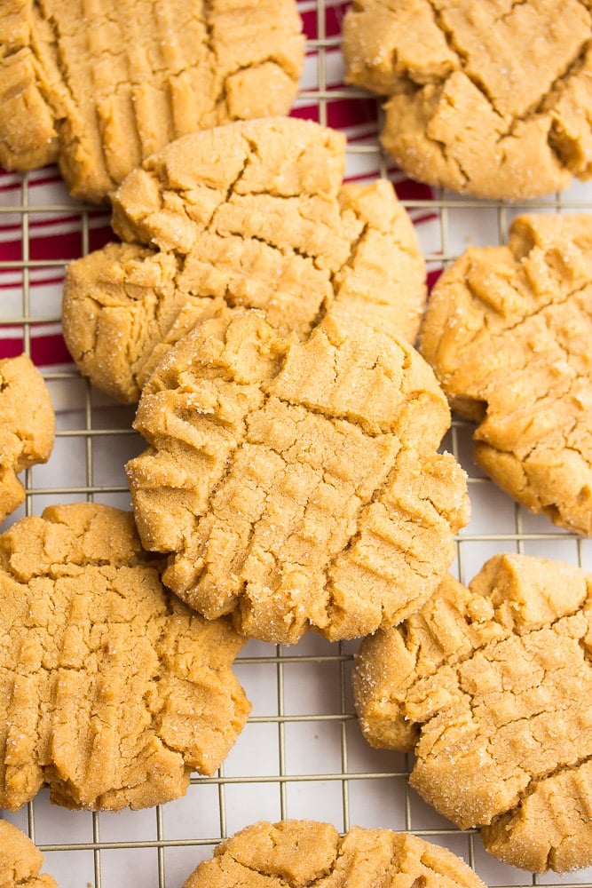 a cookie sheet with a lot of peanut butter cookies and red towel in background