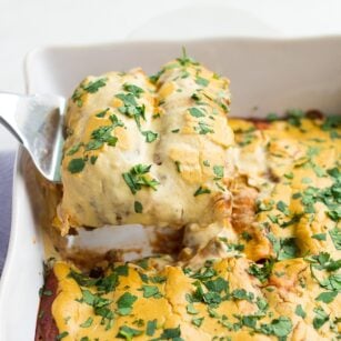 vegan enchiladas being lifted out of casserole dish