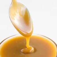vegan caramel being drizzled with a spoon into a bowl of caramel.