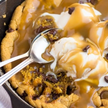 skillet cookie with caramel and ice cream with spoons.