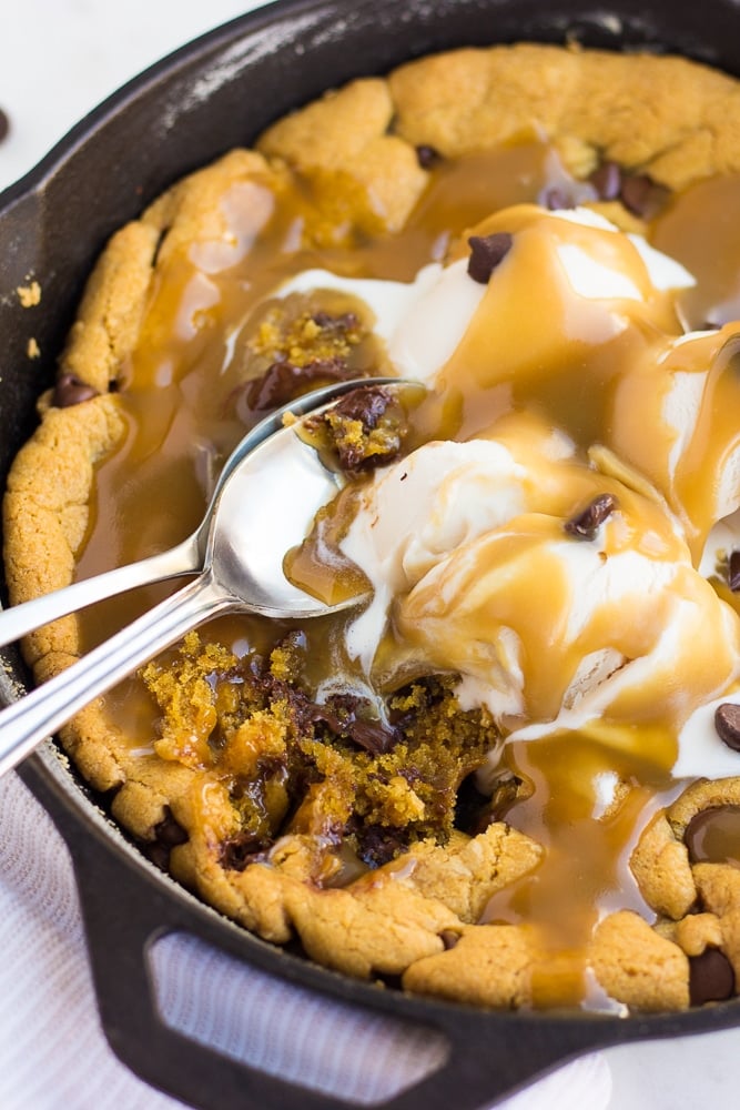 skillet cookie with caramel and ice cream with spoons.