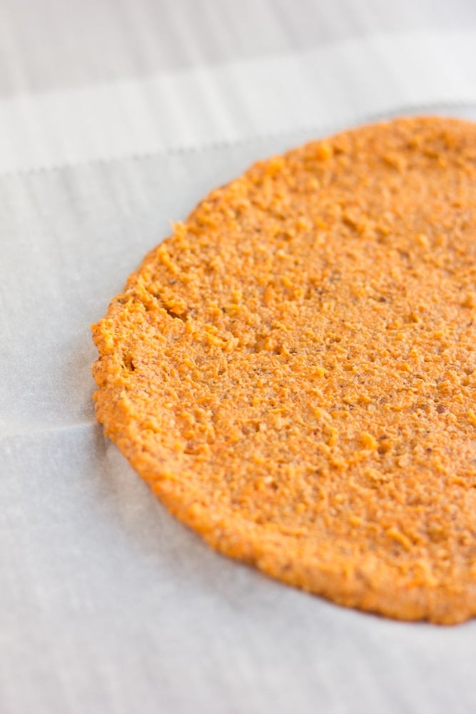 pre-cooked sweet potato pizza crust on parchment paper.