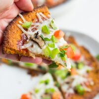 hand holding sweet potato pizza crust with toppings, cooked.