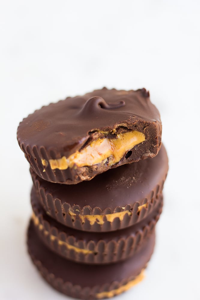 stack of vegan peanut butter cups with a bite taken out of the top one.
