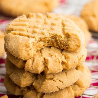 square image of a stack of peanut butter criss cross topped cookies, red and white towel in background
