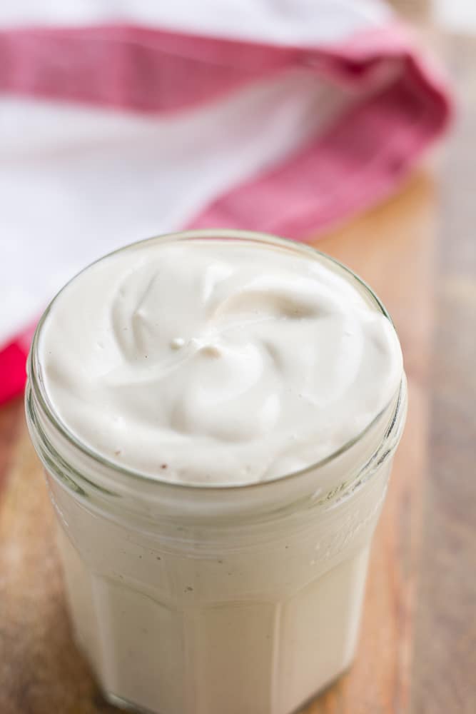 vegan mayo in a glass jar with red towel in background.