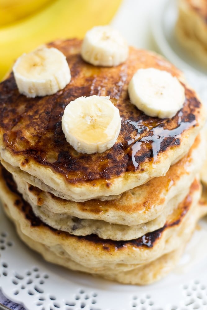 looking down on stack of pancakes with banana slices on top and syrup.