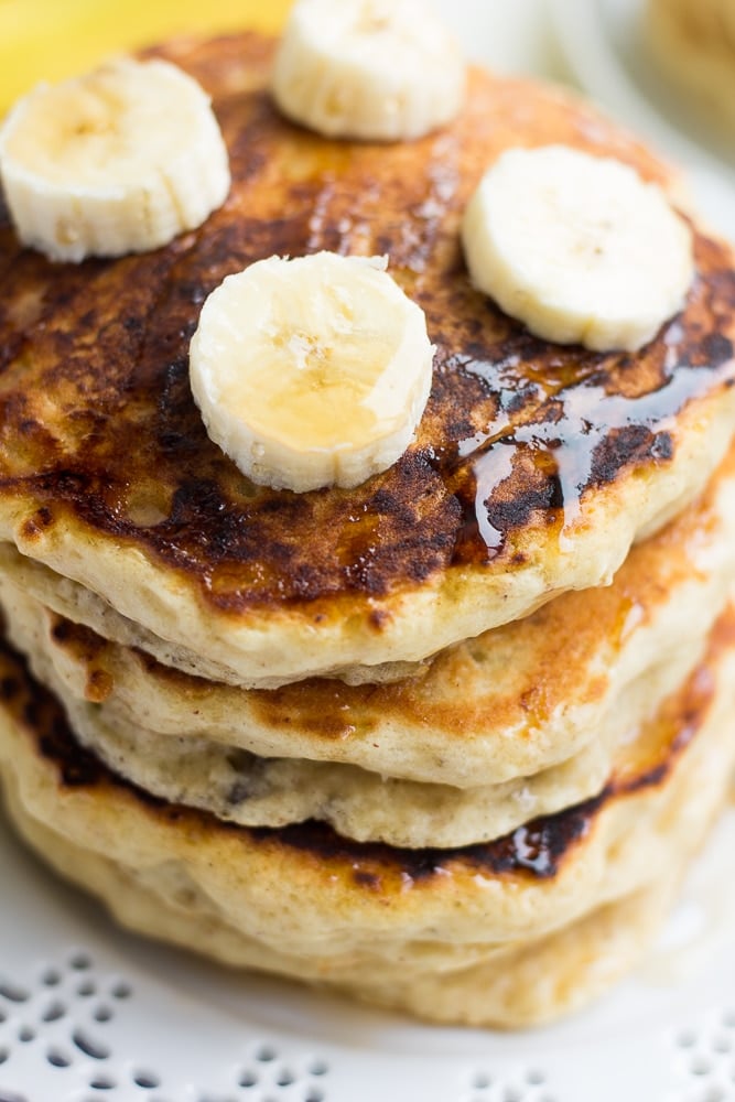 close up stack of banana pancakes with banana slices on top.