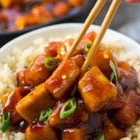 sriracha tofu being picked up with chopsticks from a bowl