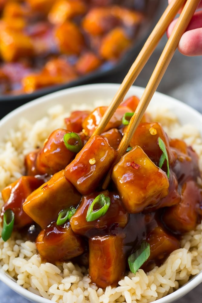 sriracha tofu being picked up with chopsticks from a bowl