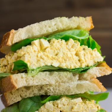 close up of vegan egg salad in a sandwich with lettuce.