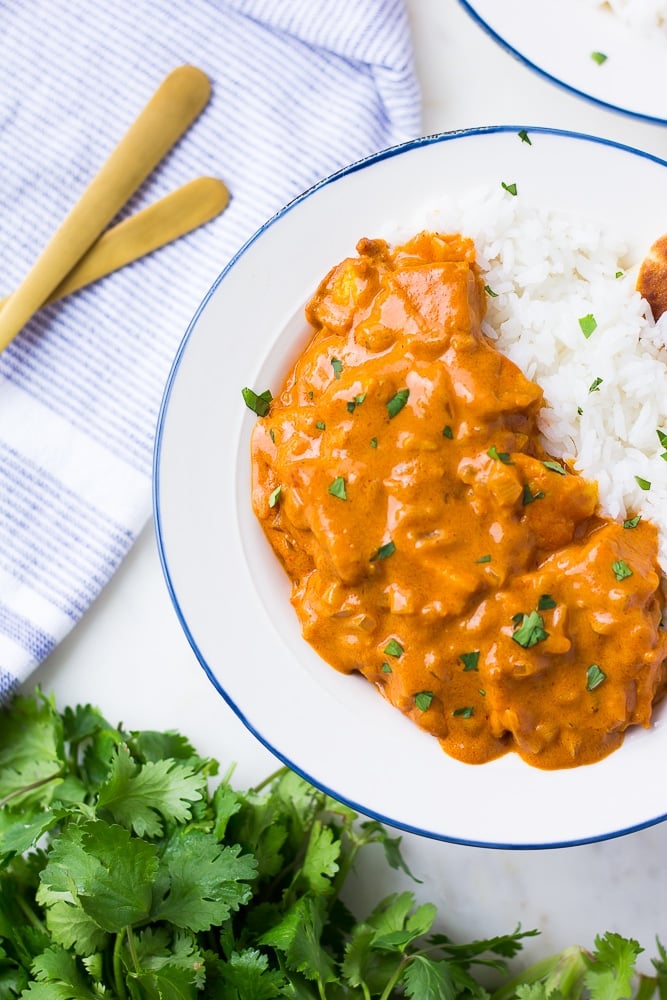 looking down on vegan butter chicken with rice, cilantro in background.