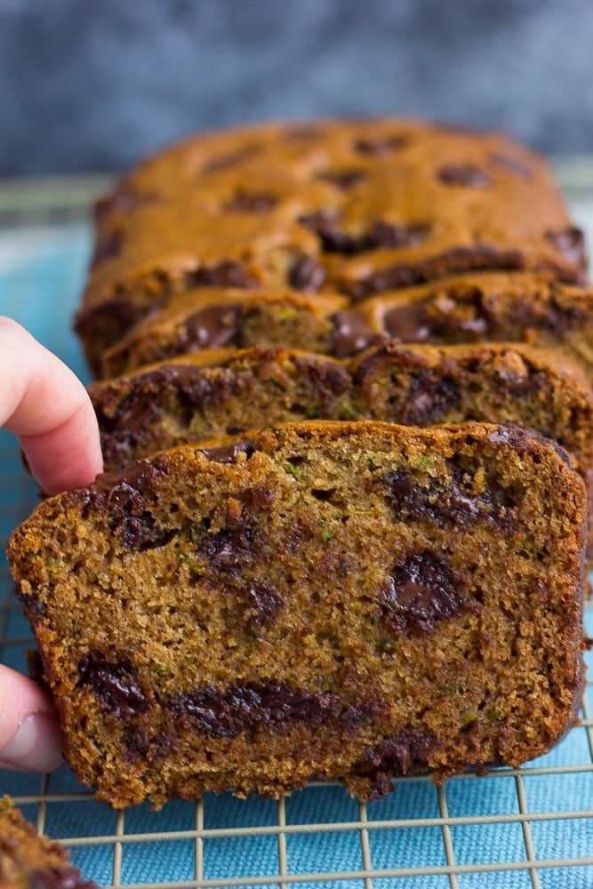 vegan zucchini bread with a hand grabbing one slice