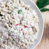 close up of macaroni salad with dill in background.