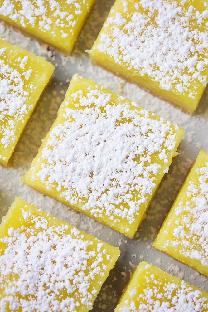 looking down on lined up vegan lemon bars with powdered sugar.