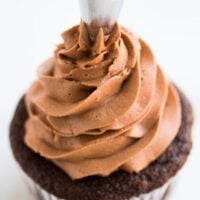 vegan chocolate frosting being piped onto a cupcake
