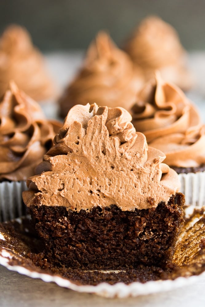 a chocolate cupcake that is sliced in half with more cupcakes behind it.