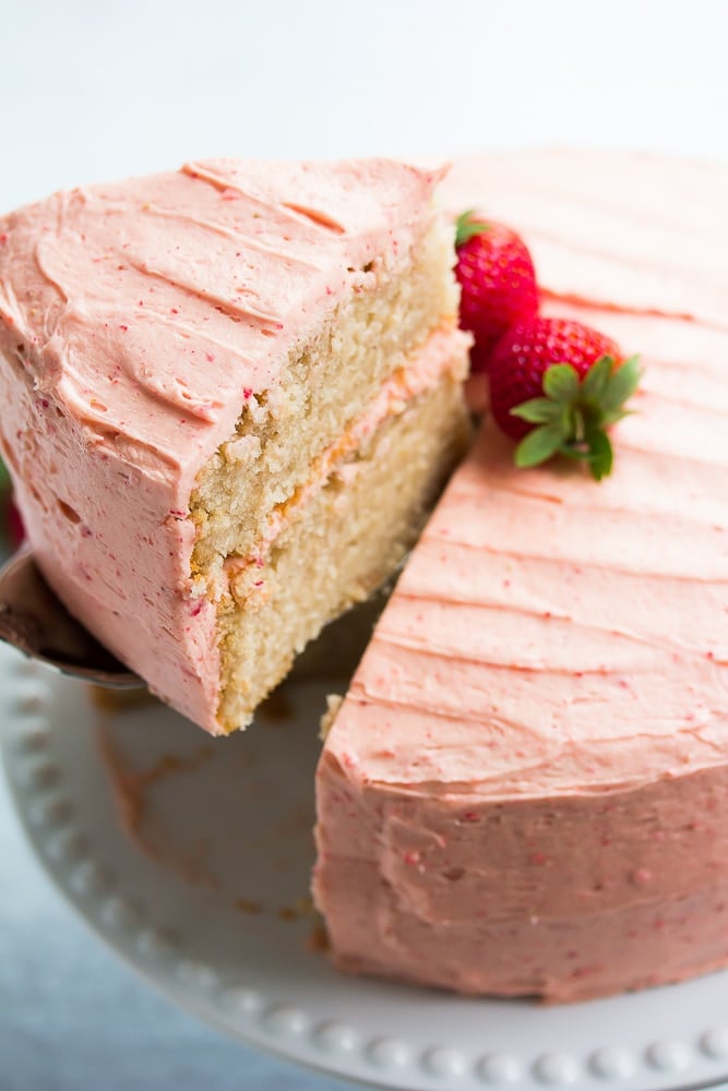 piece of vegan strawberry cake being lifted out of whole cake