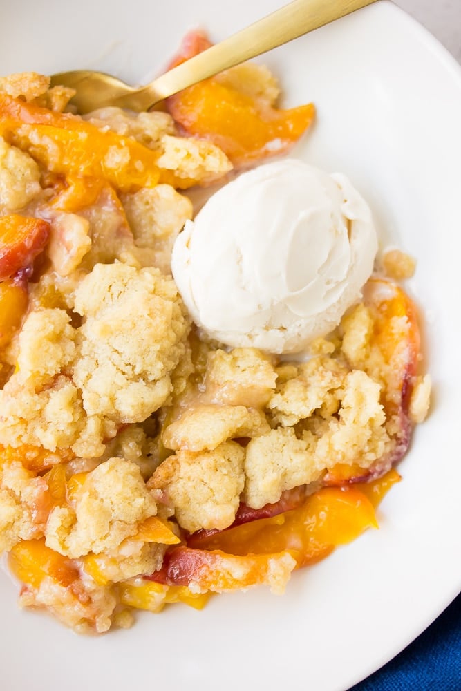 peach cobbler in a white bowl with ice cream