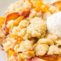 serving of vegan peach casserole in a bowl with soy vanilla ice cream scoop