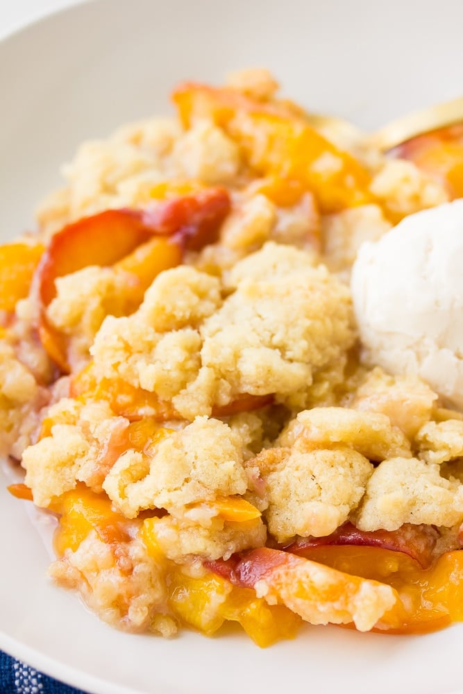 serving of vegan peach casserole in a bowl with soy vanilla ice cream scoop