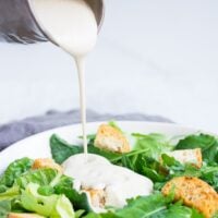 square image of white dressing poured on salad